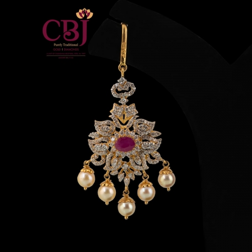 Traditional maang tikka adorned with ruby, emeralds and featuring pearl drops.