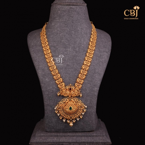 This grand long haram studded with pearls, cz and emerald stones is a fine example of how tradition meets opulence.