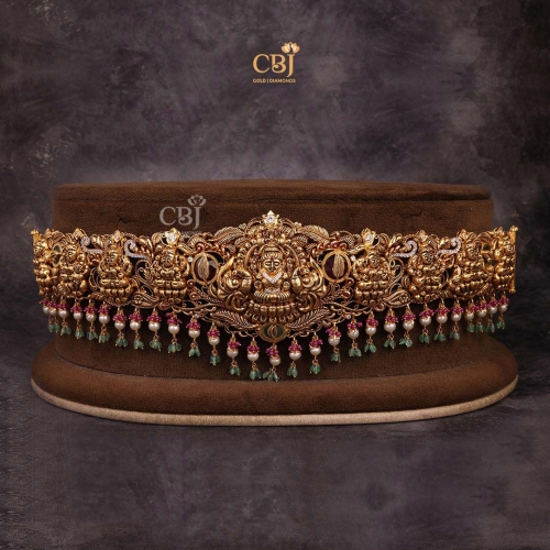 Embrace the Goddess of wealth on your auspicious day. An antique vaddanam featuring a culmination of stones like CZs, pearls and rubies.