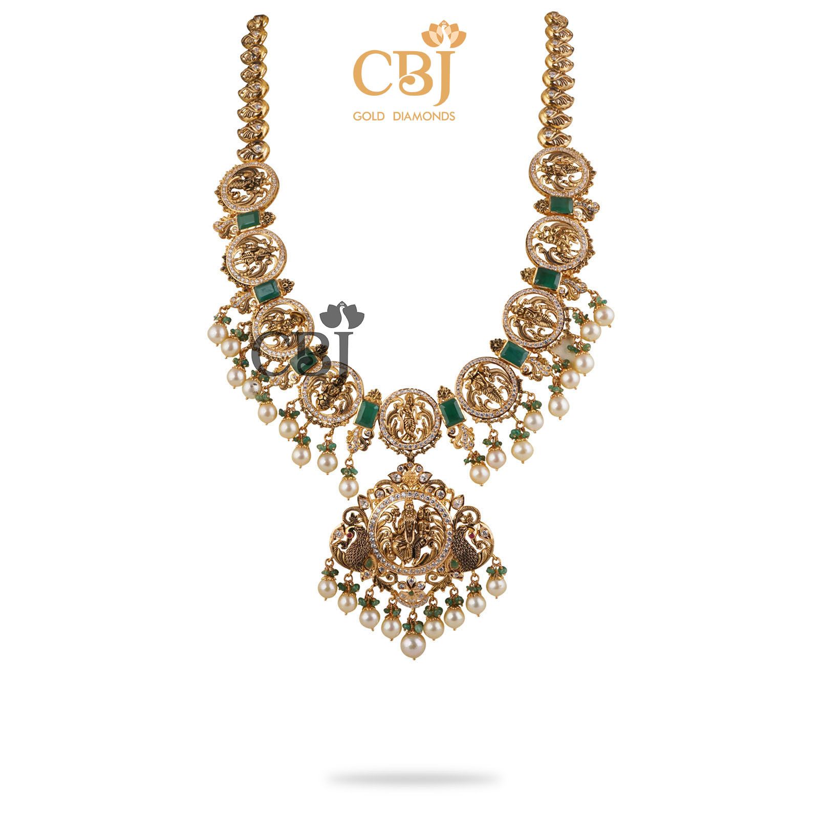 This stunning Dasavataram Semi long haram is an incredible marvel in design featuring emerald stones and suspended pearl drops.