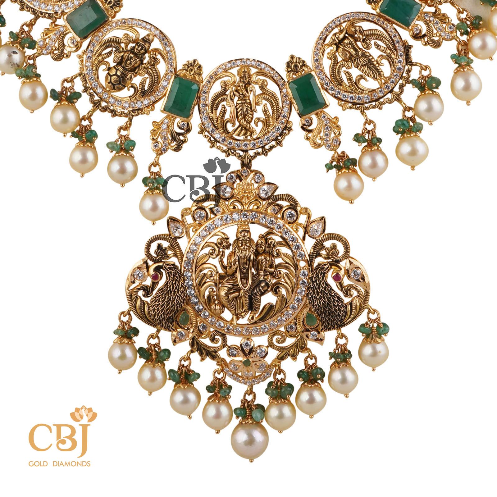 This stunning Dasavataram Semi long haram is an incredible marvel in design featuring emerald stones and suspended pearl drops.