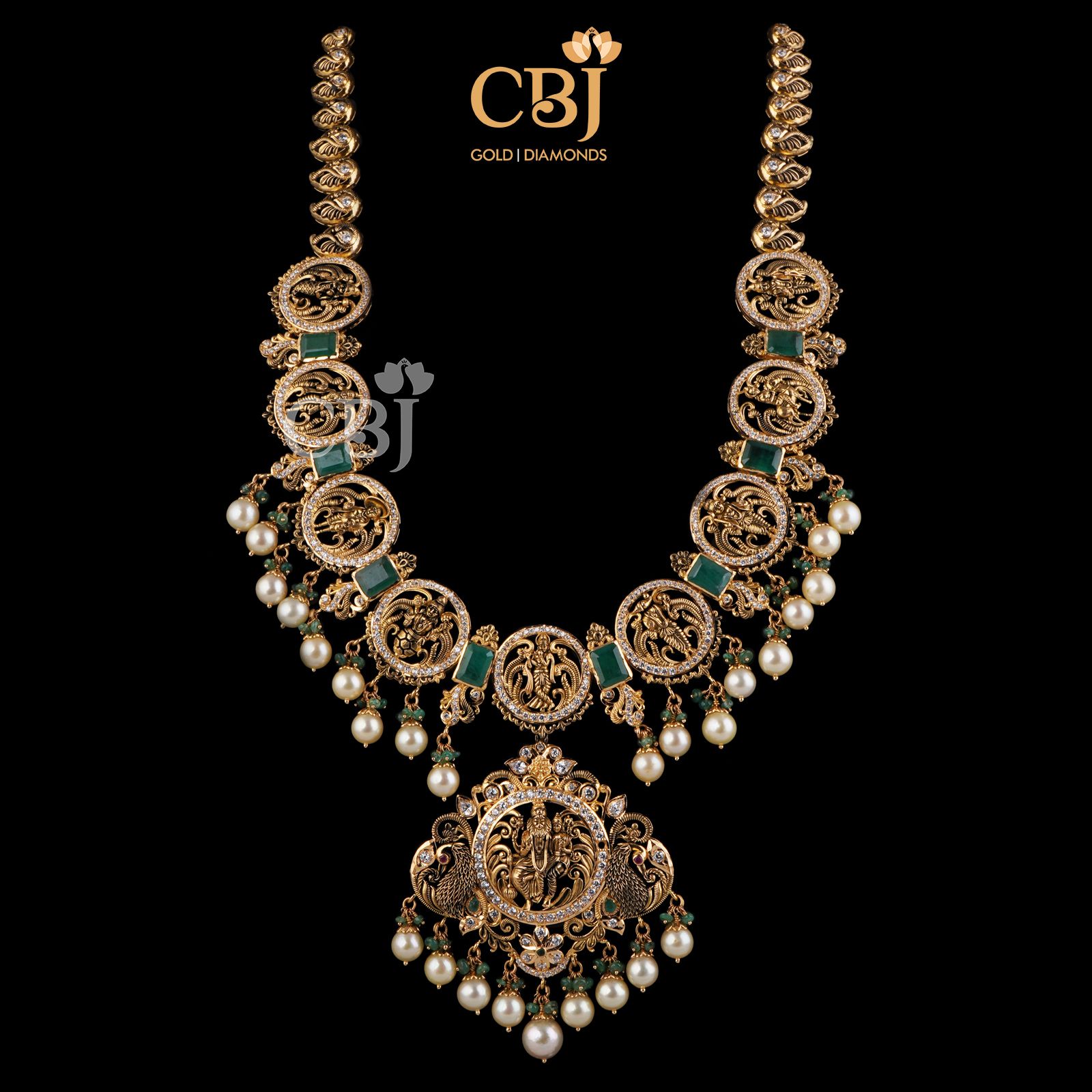 This stunning Dasavataram Semi long haram is an incredible marvel in design featuring emerald stones and suspended pearl drops.