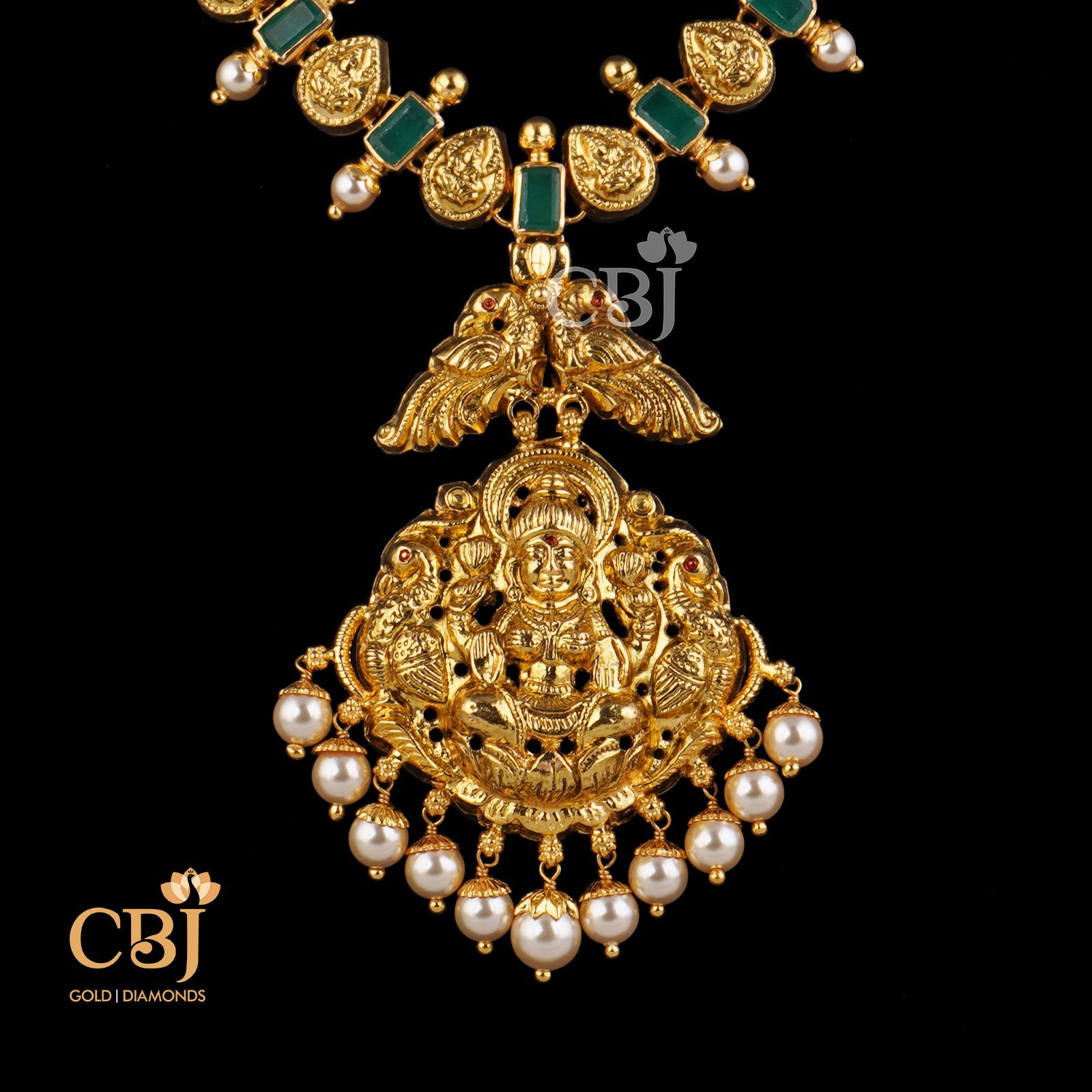 A classic traditional Lakshmi necklace studded with symmetrical emerald stones.
