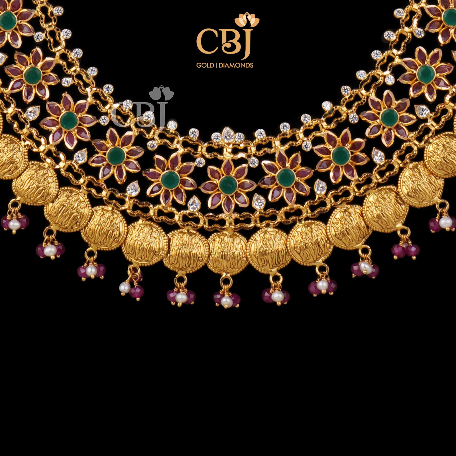 A floral patterned kasu U-haram studded with rubies and emeralds.