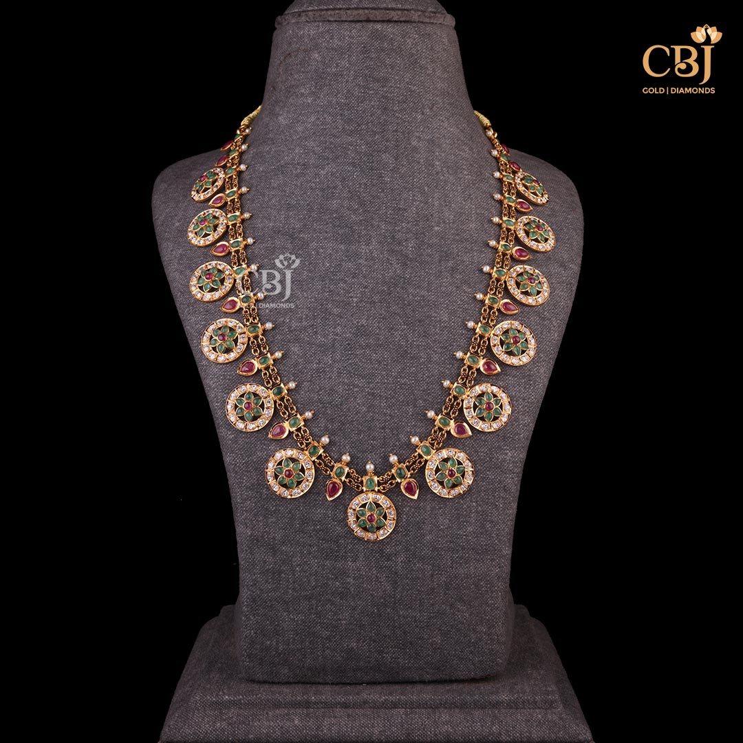 A slim long CZ pachi haram featuring a kasu design studded with CZ stones, rubies and emeralds.