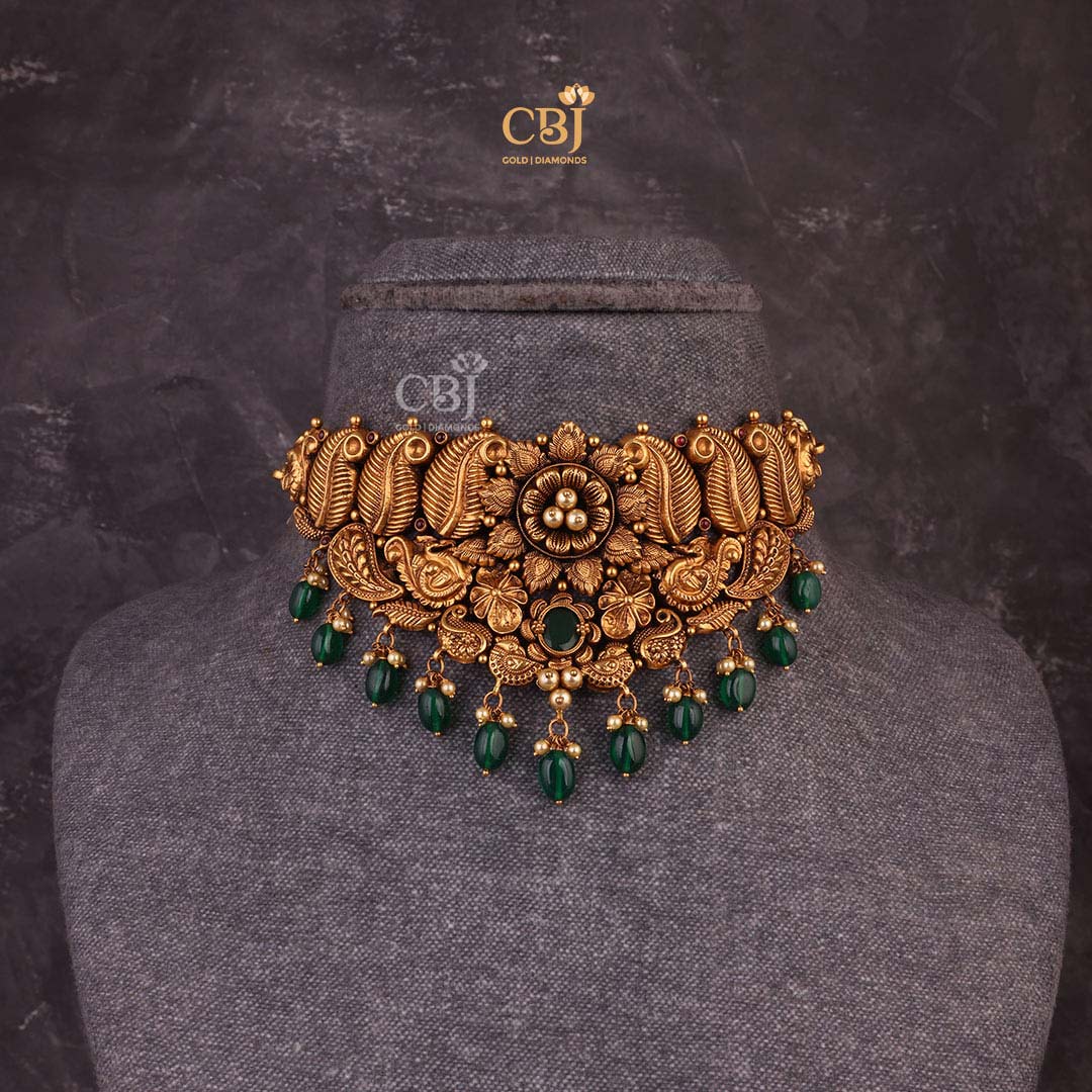 Antique choker with a floral design featuring leaf like motifs decorated with pearls and emeralds.