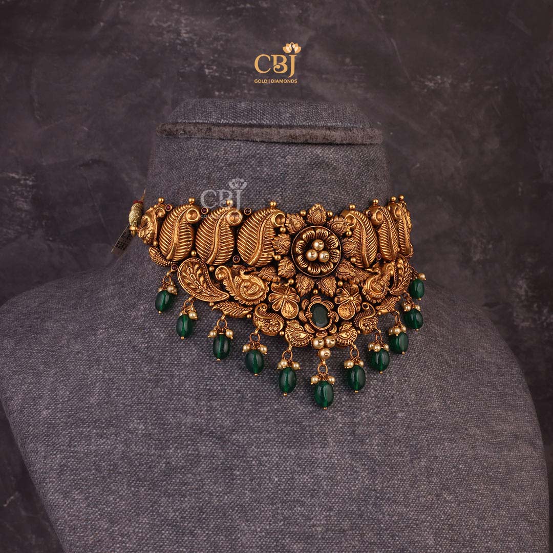 Antique choker with a floral design featuring leaf like motifs decorated with pearls and emeralds.