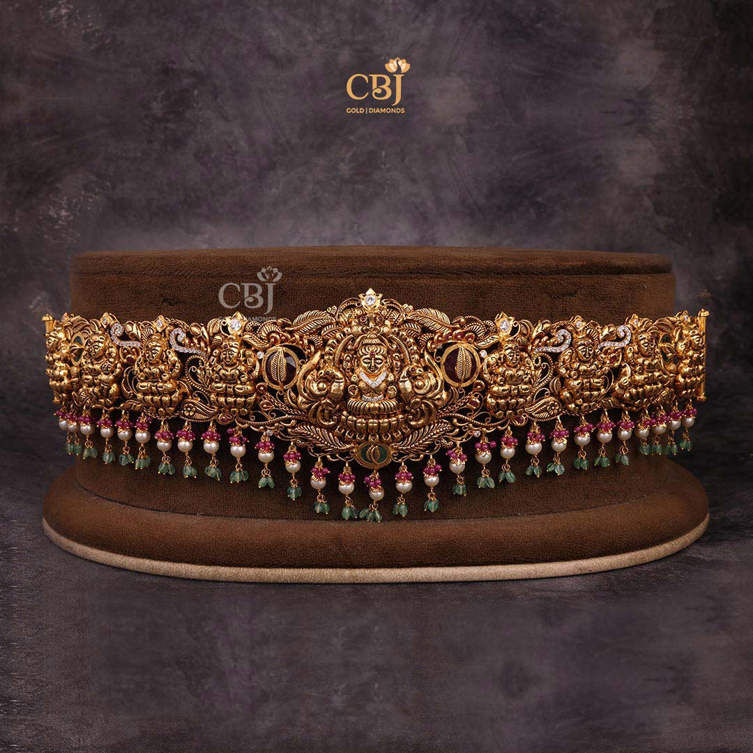 Embrace the Goddess of wealth on your auspicious day. An antique vaddanam featuring a culmination of stones like CZs, pearls and rubies.