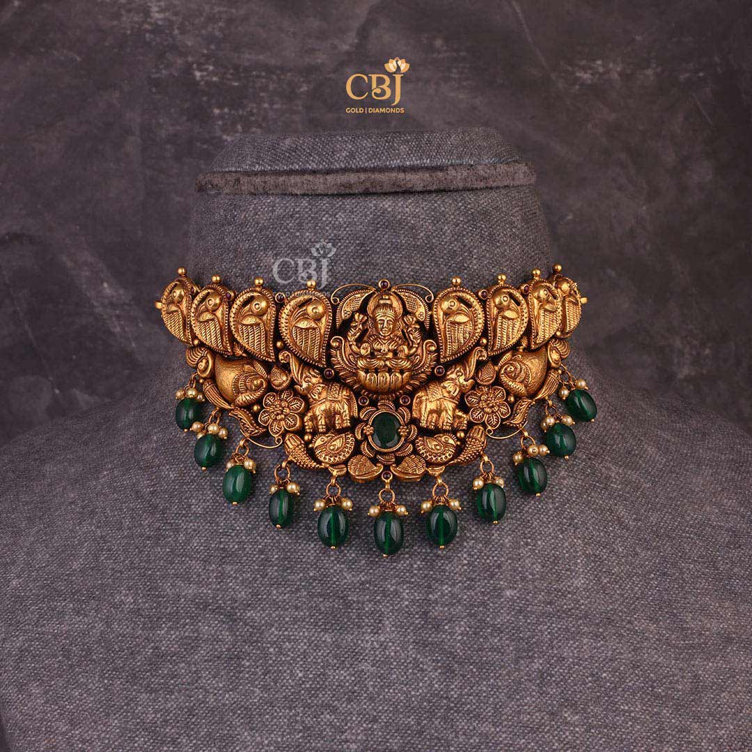 A bold Gajalakshmi choker embellished with emerald stones.