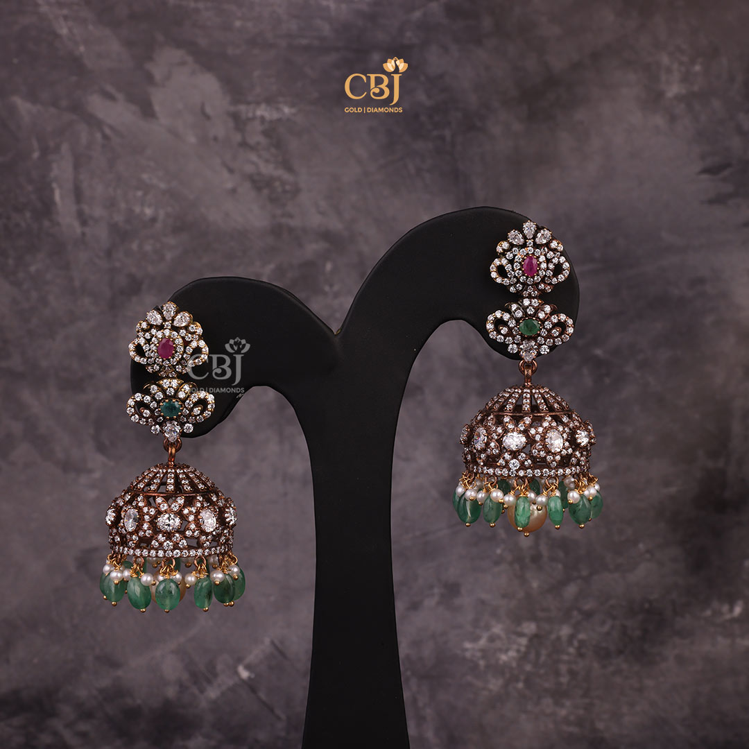 This stunning CZ jhumka featuring emerald beads and rubies is a subtle design that is sure to captivate hearts.