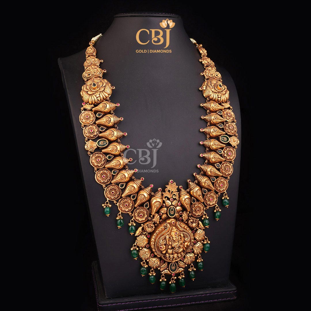 This antique long haram is a divine depiction of Goddess Lakshmi with unique shell shaped motifs.