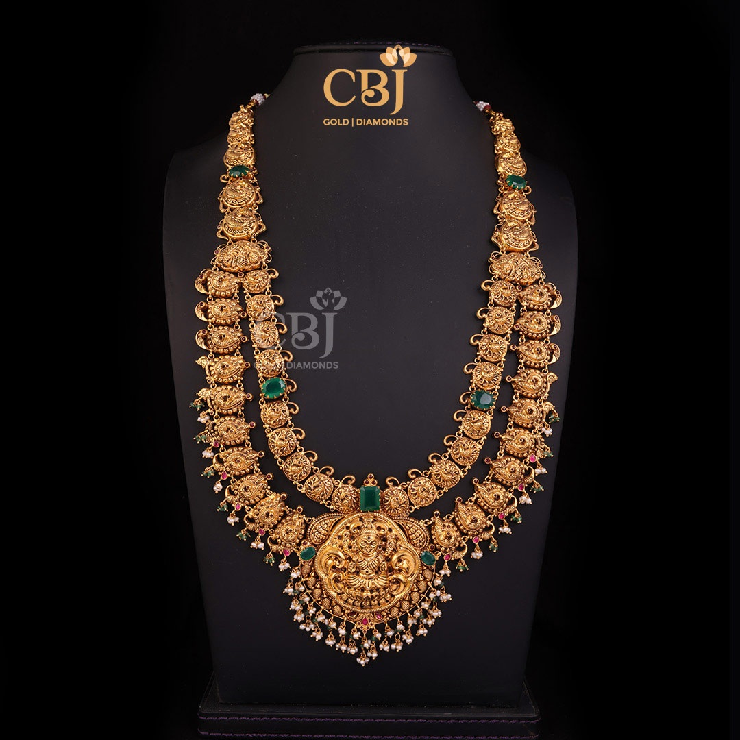 A 2 step antique Lakshmi haram featuring a graceful design decorated with rubies, emeralds and pearls.