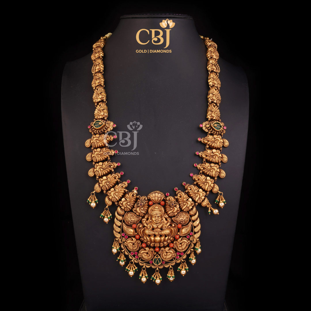 A statement antique Lakshmi long haram embellished with emeralds, pearls and coral stones.