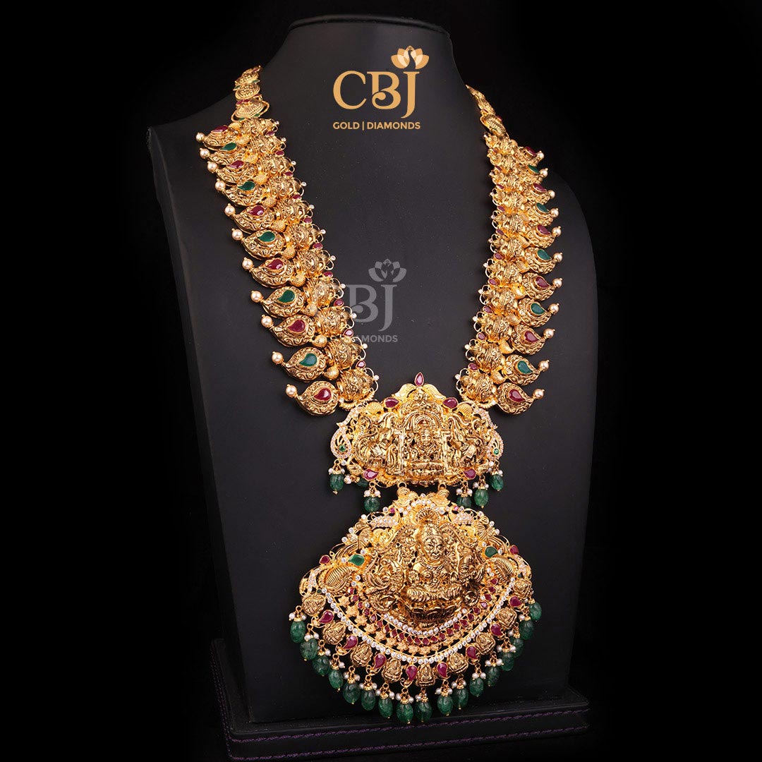 A divine CZ pachi light weight Lakshmi haram featuring mango motifs adorned with rubies and emeralds.